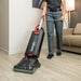 a person vacuuming a hard floor in a hotel background using the Sanitaire EON SC5500B commercial grade vacuum